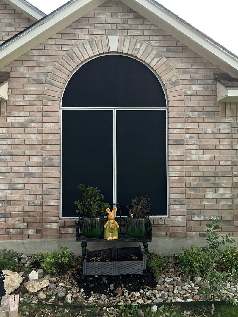 Custom arched round-top solar screen fitted to a brick gable window