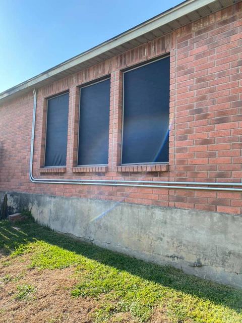 Three black solar screens on a red brick San Antonio home in full afternoon sun